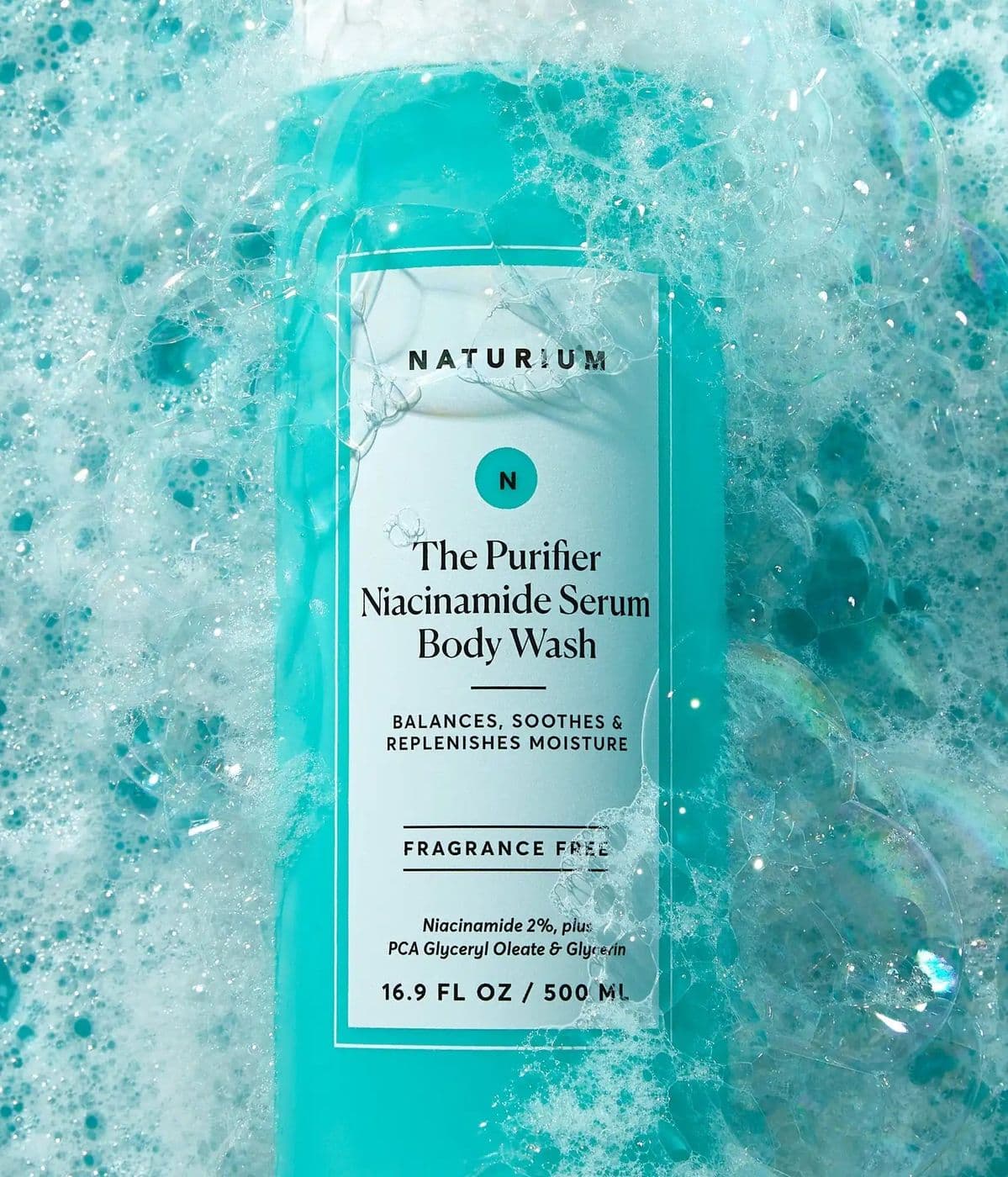 A turquoise body wash bottle lying in aqua foam and bubbles