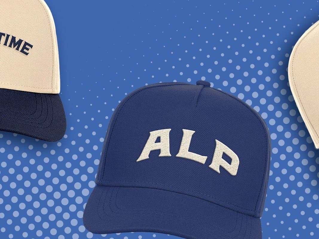 A navy ALP cap with the ALP wordmark between two cream caps on a blue halftone pattern.