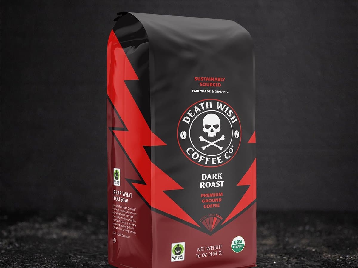 A black and red bag of Death Wish Coffee Dark Roast ground coffee standing on dark ground.