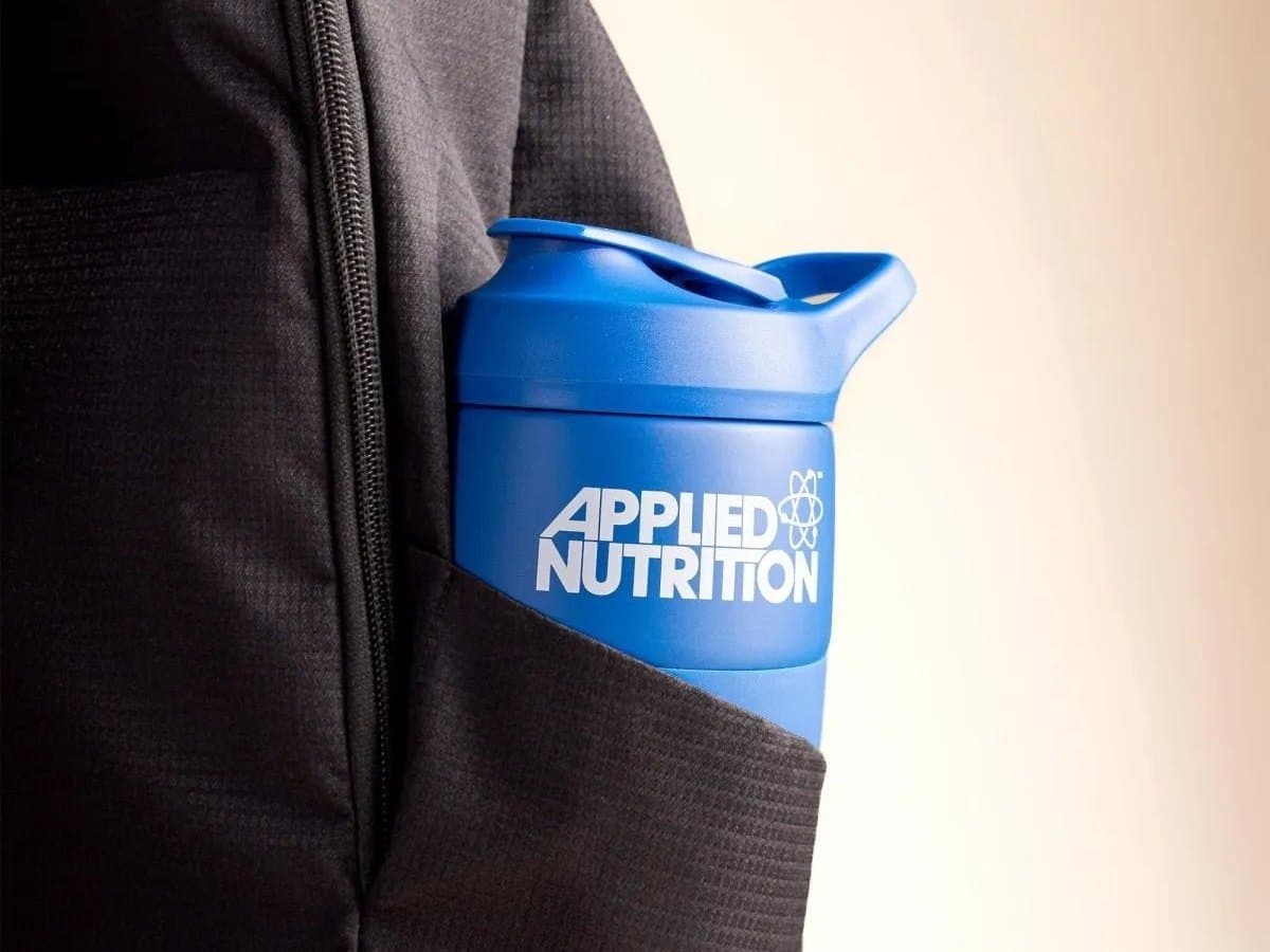 A blue shaker bottle tucked into the side pocket of a black backpack.
