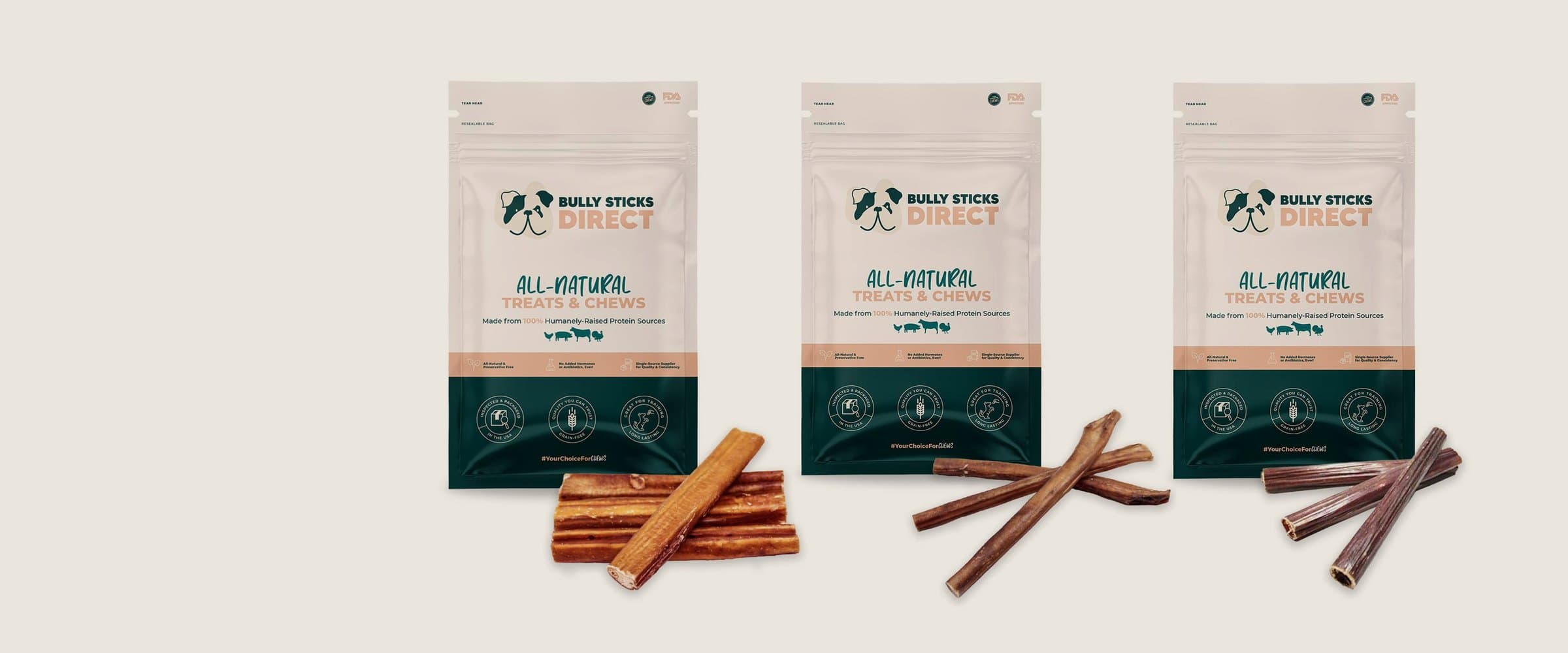 Bully Sticks Direct treat pouches standing in a row on a warm sand backdrop, chews in front of each.