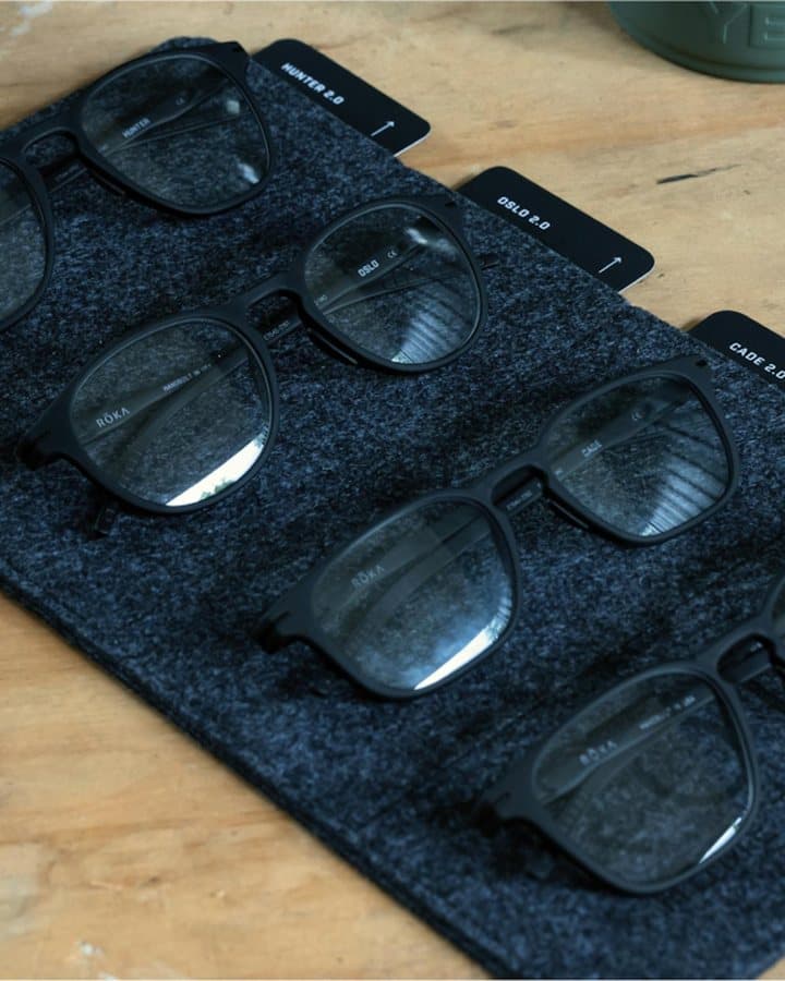 Rows of ROKA eyeglass frames laid out on a dark felt display mat.