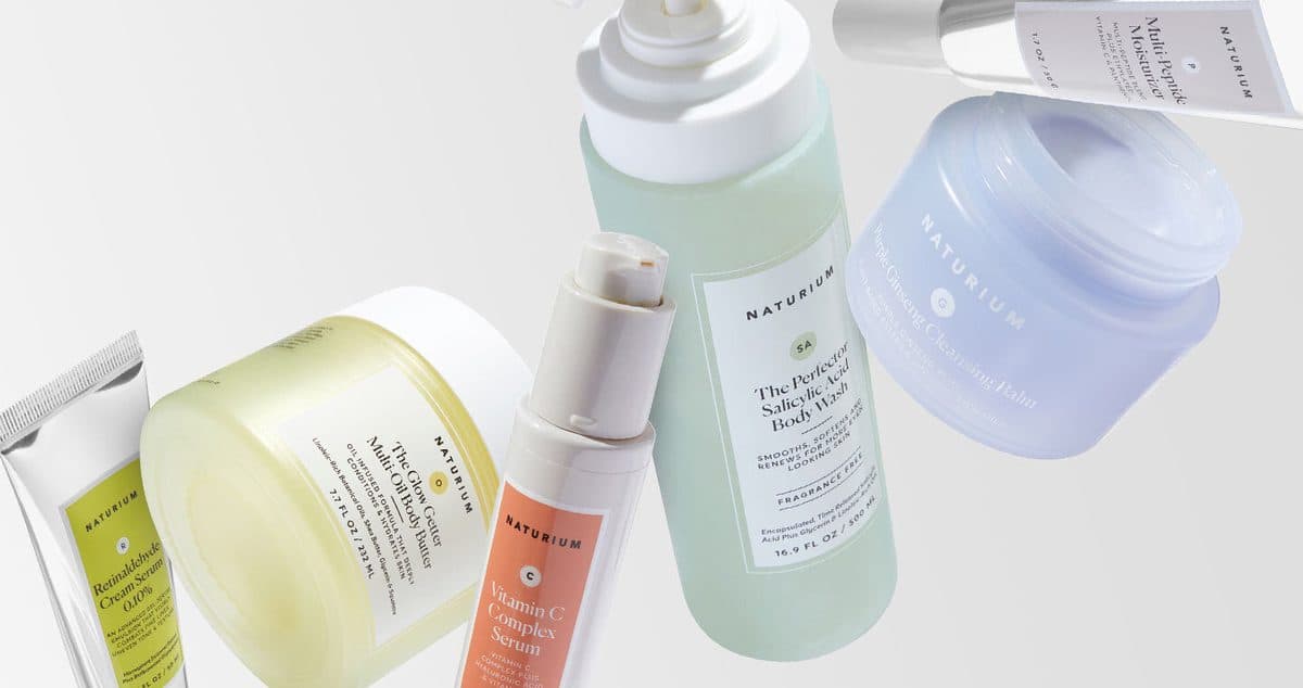 Naturium body wash, body butter and serums floating against a pale grey backdrop.