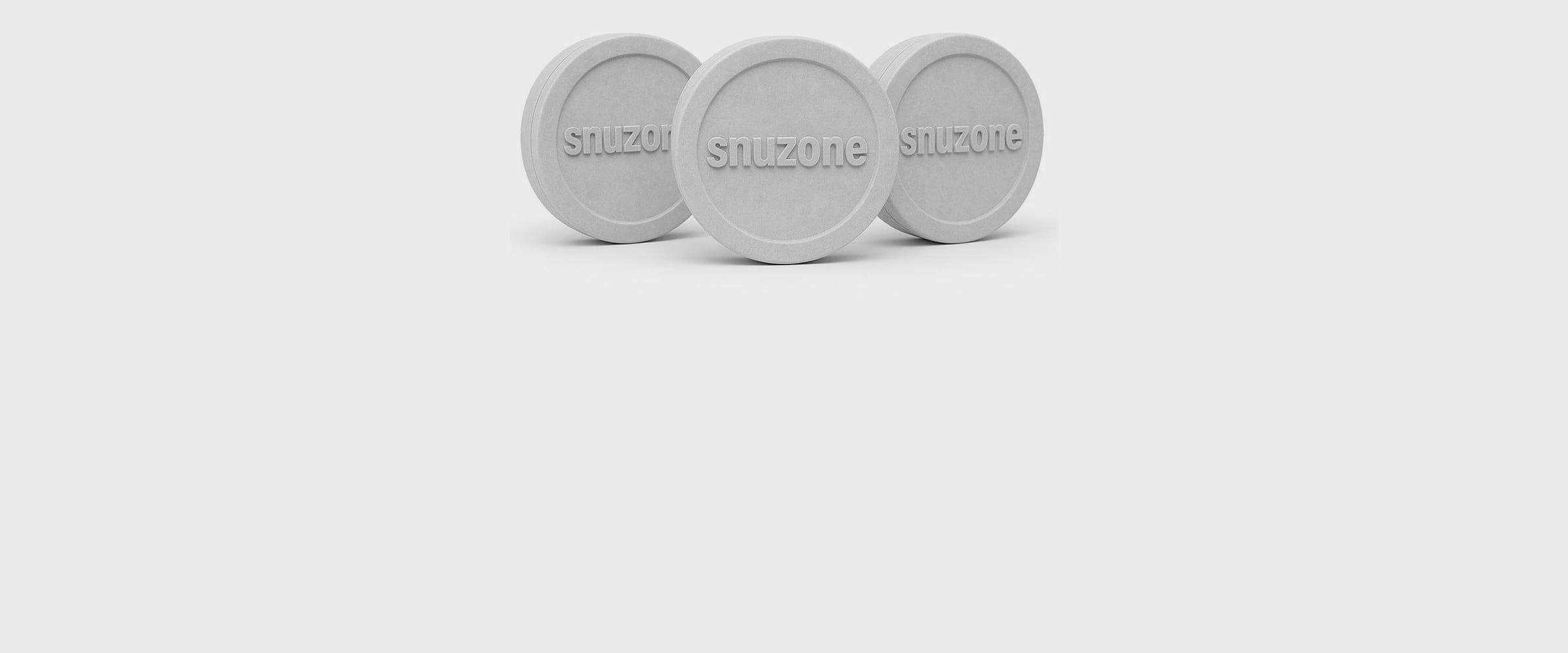 Three round white tins embossed with the Snuzone wordmark, standing on edge on a pale grey ground.